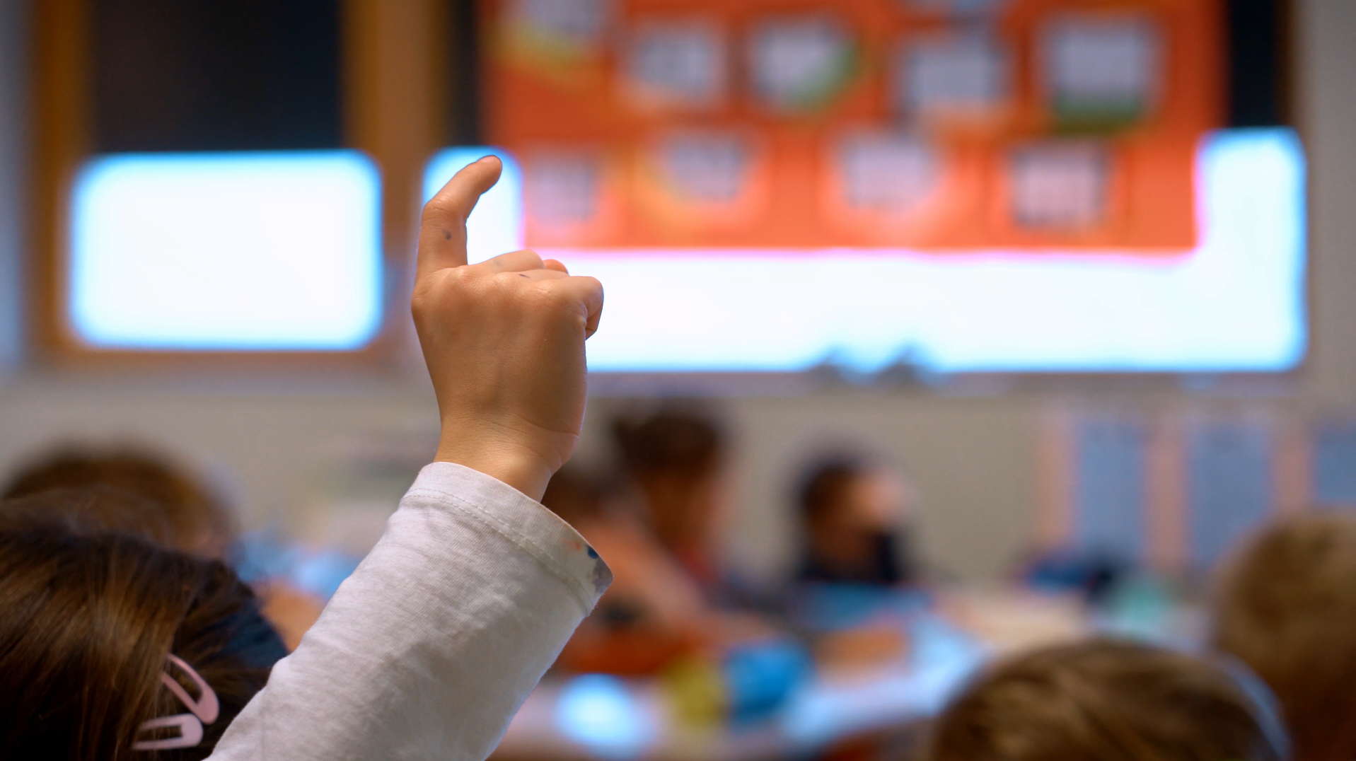 Enfant levant la main dans une salle de classe, lors d’un temps d’apprentissage à l’école.